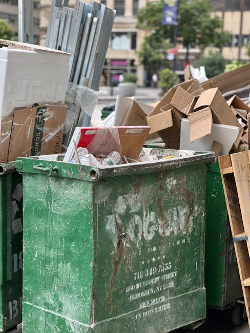 A large collection of overflowing rubbish bins and scattered waste bags located on a paved sidewalk in front of a commercial building. The waste includes black and clear plastic trash bags, flattened 